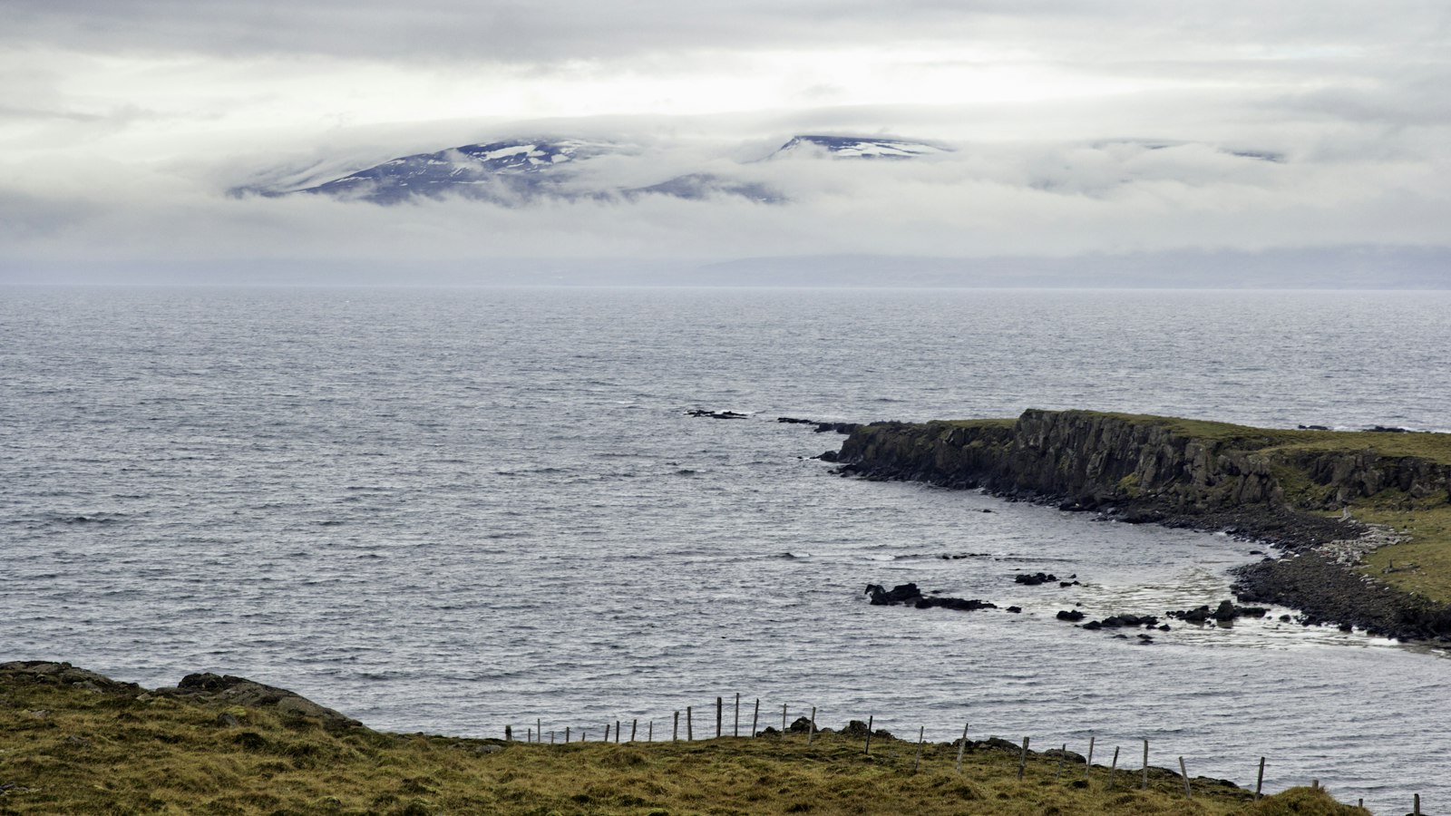 Rocky coastline and low cliffs with sea and distant mountains