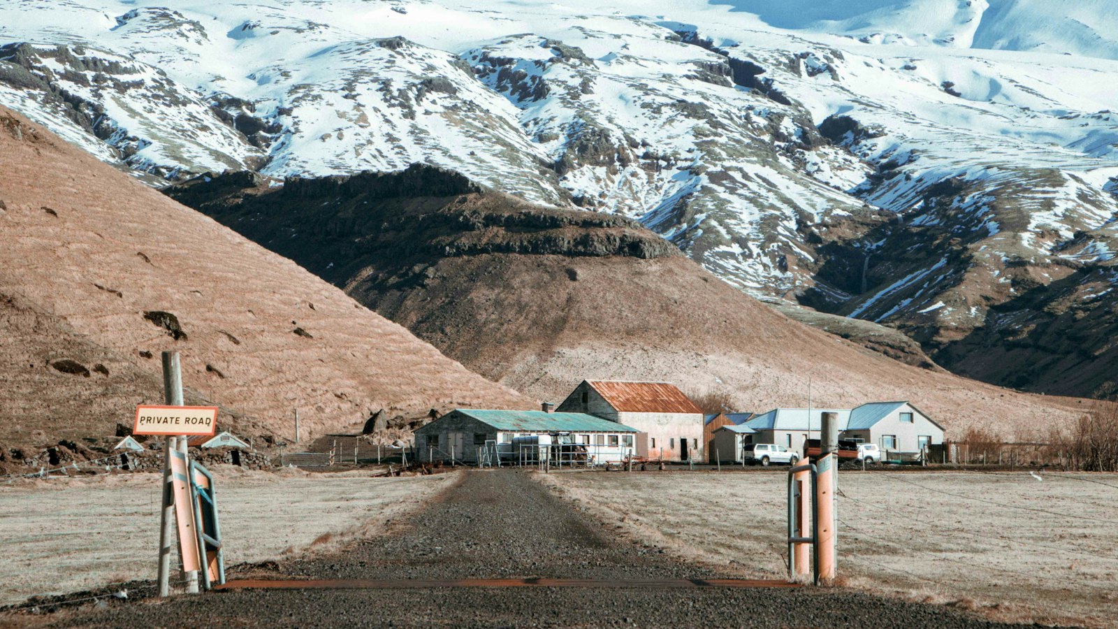 Farm buildings beneath snow‑dusted mountains