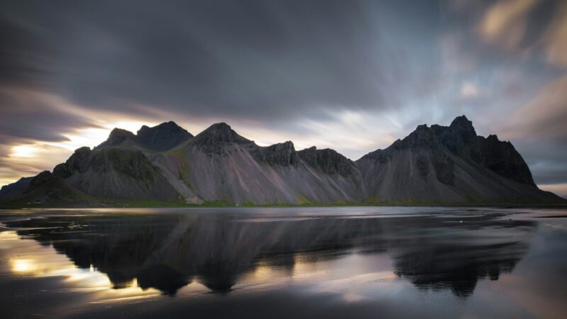 Mountain range reflected in a calm sea with dramatic skies