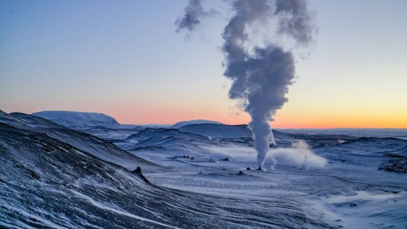 Steam plume rising from a geothermal site in a snowy valley