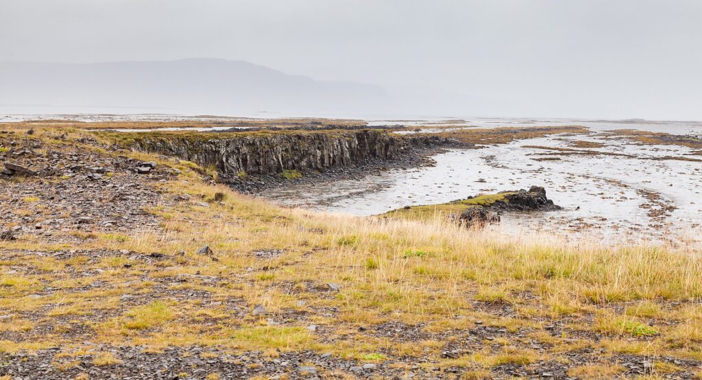 Rocky shoreline and tidal channels under a misty sky (Húnaþing vestra)