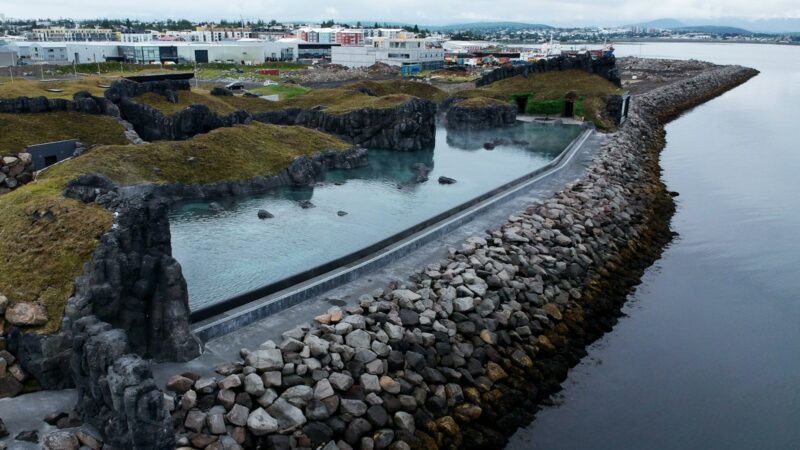 A geothermal bathing pool by a river from above