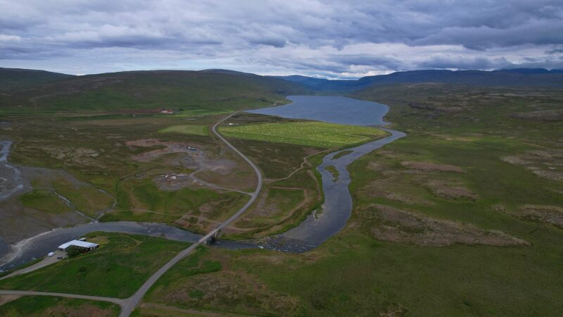 Lake in a valley with surrounding hills and a winding river (Haukadalur)