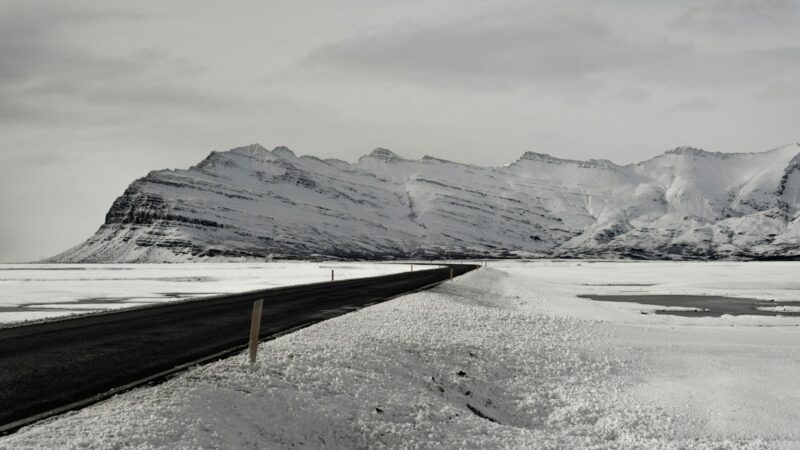 Snow-covered road leading toward a range of mountains