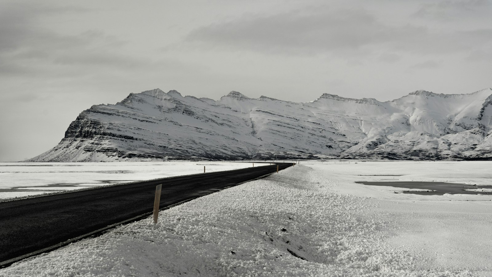 Snow-covered road leading toward a range of mountains