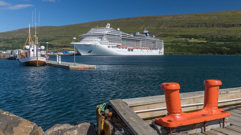 Large cruise ship moored beside a small boat and quay (Oddeyri)