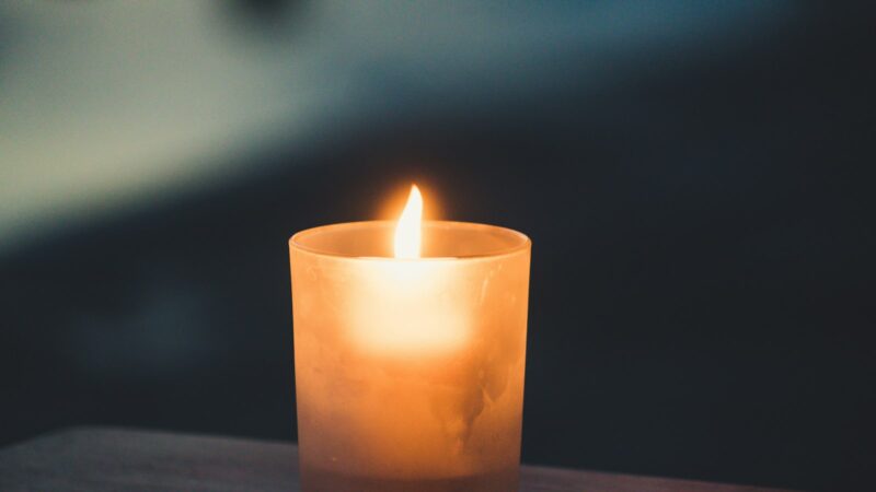 A lit candle in a frosted glass holder