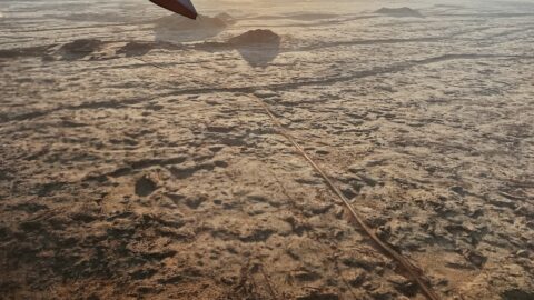 View of rough volcanic terrain from an aircraft window and wingtip