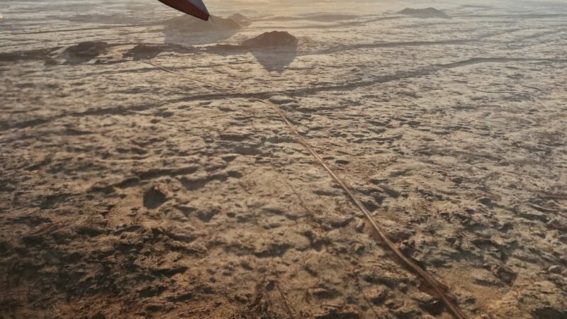 View of rough volcanic terrain from an aircraft window and wingtip