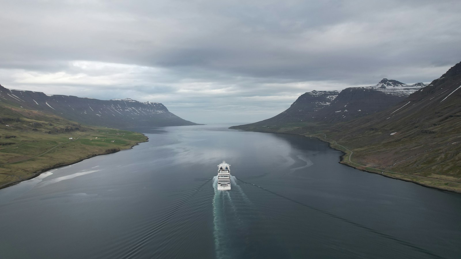 A cruise ship sailing into a fjord in the Westfjords