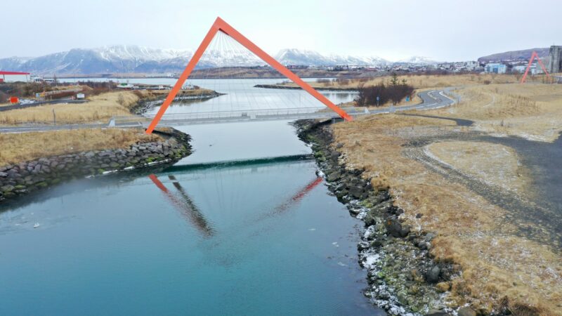 A red steel bridge over a glacial river in winter