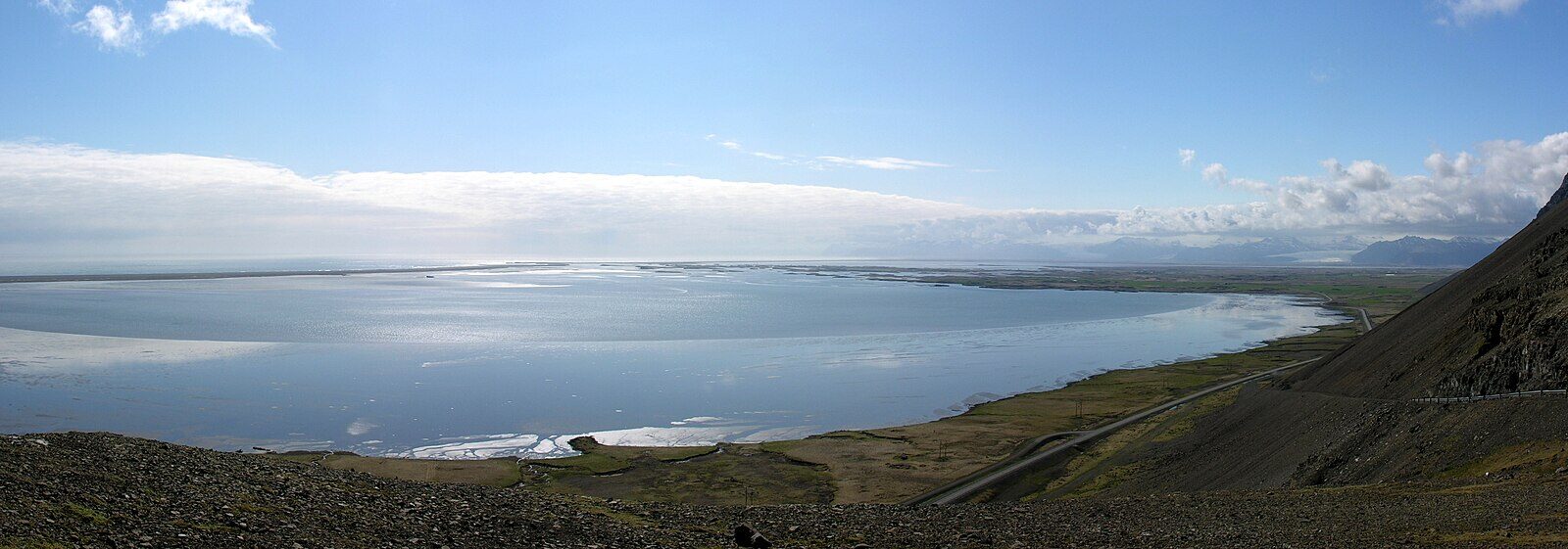 Coastal bay with a narrow road running along the shoreline (Almannaskarð tunnels)