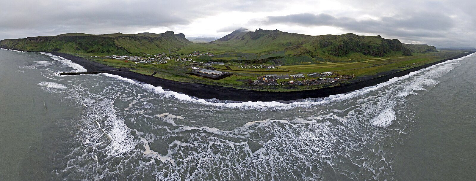 Coastal village with black sand shore and waves reaching the shoreline (Vík í Mýrdal)
