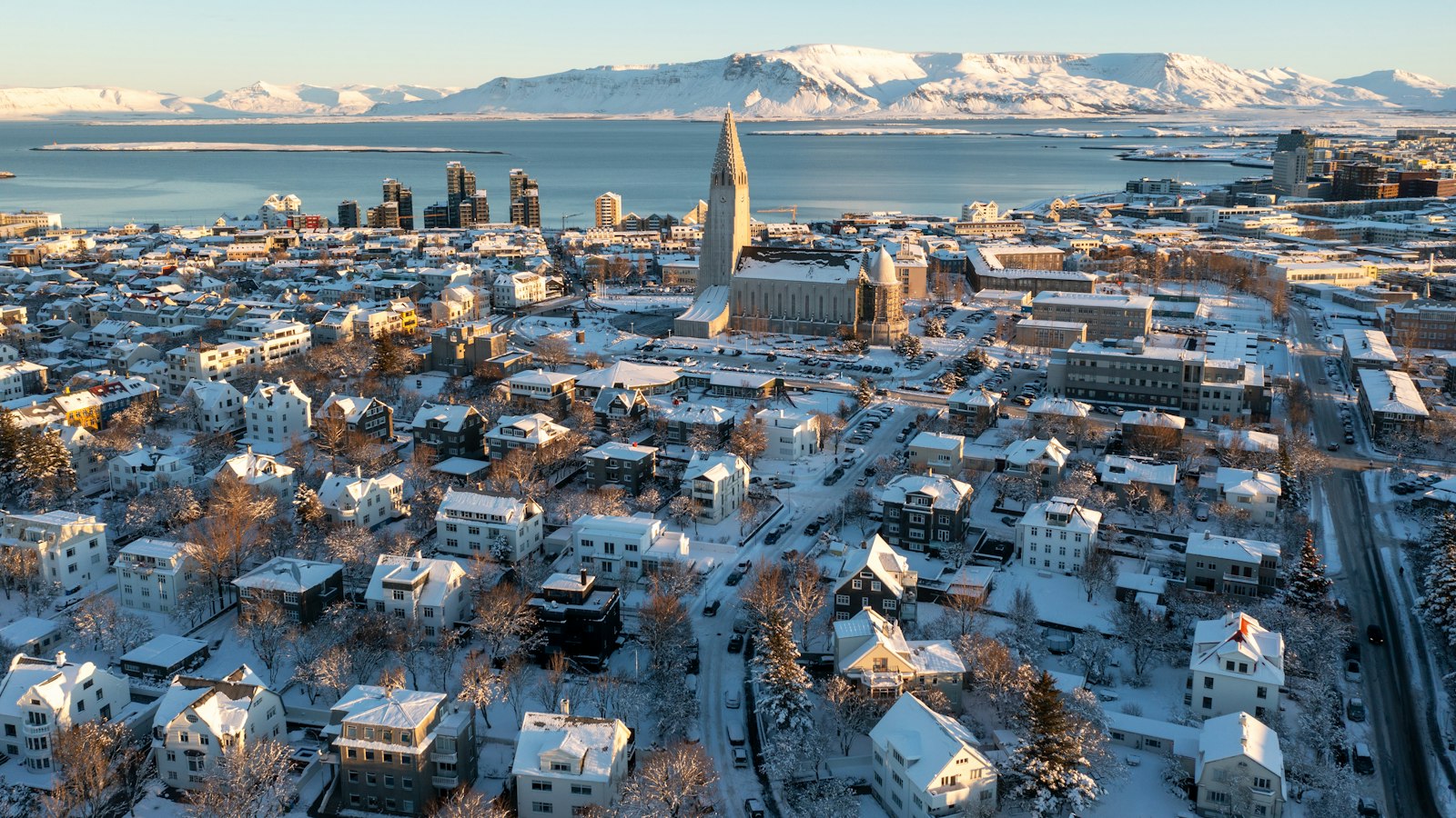 A snow‑covered cityscape with a prominent church tower and harbour