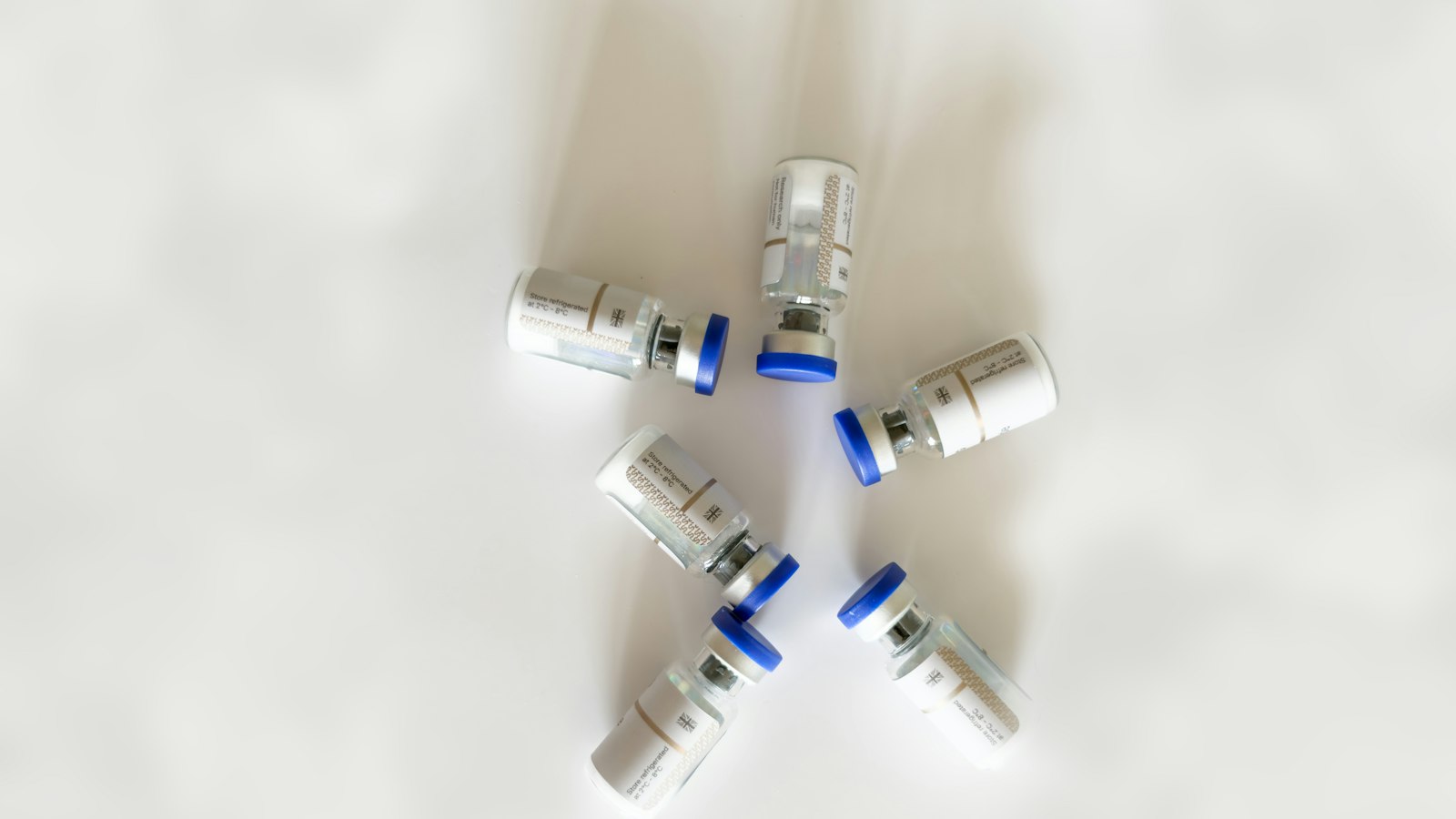Small medicine vials with blue caps on a white background