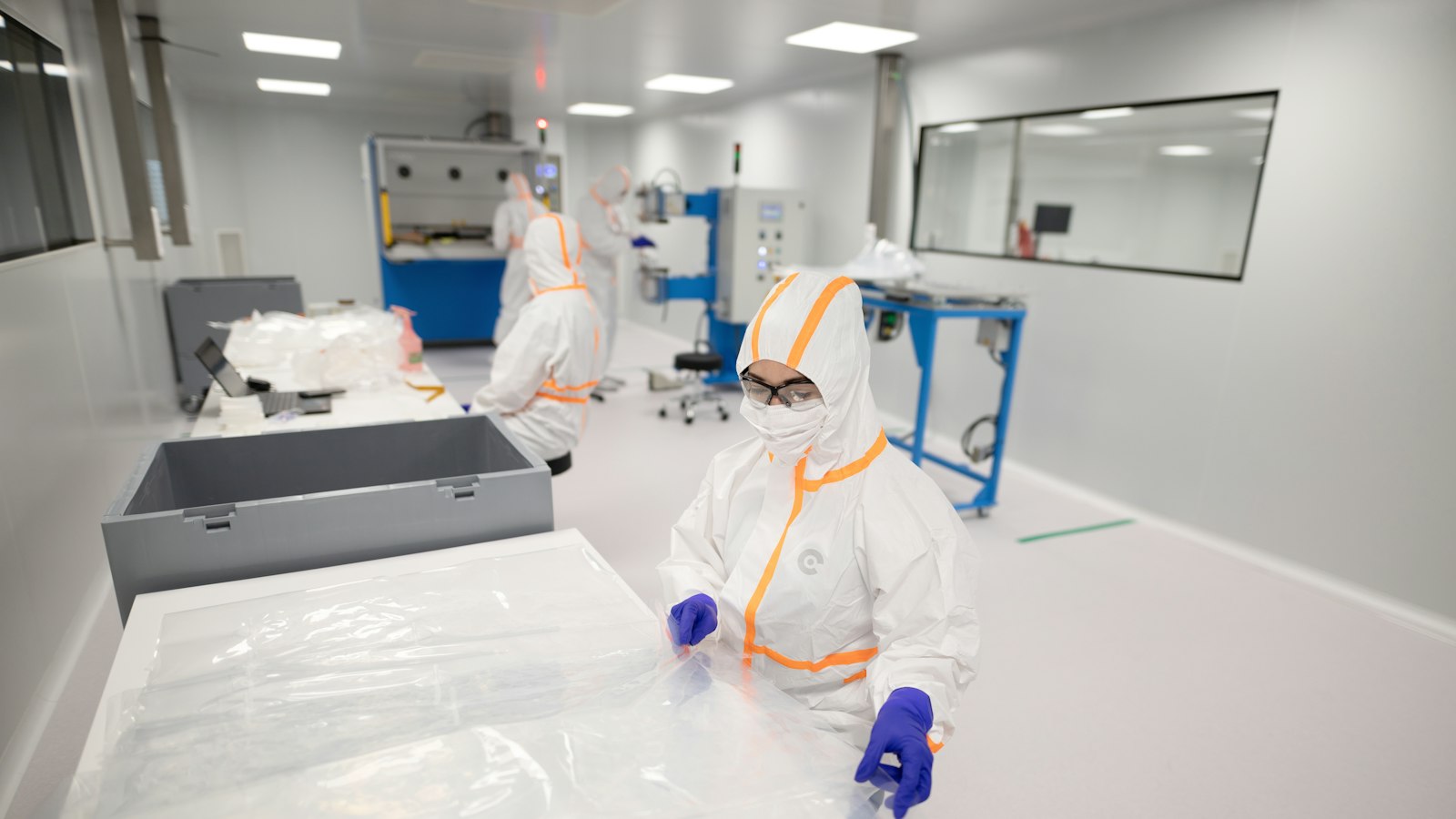 Workers in full protective suits inside a sterile cleanroom
