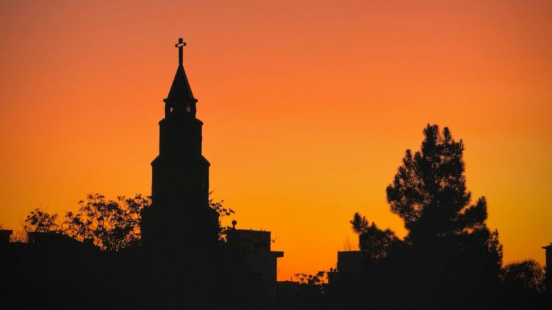A church steeple with a cross against an evening sky