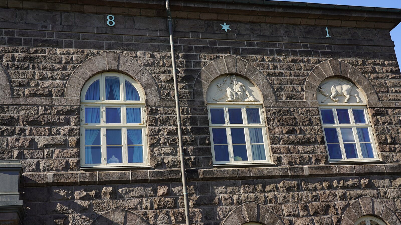 Stone facade of a government-style building with arched windows (Alþingi)