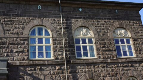 Stone facade of a government-style building with arched windows (Alþingi)