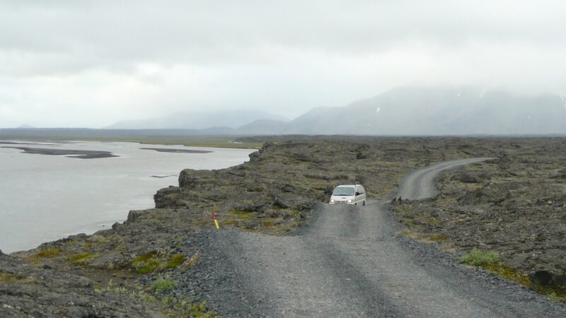 Gravel track along a rocky shoreline with a vehicle on the road