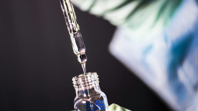 A pipette dispensing liquid into a small glass vial