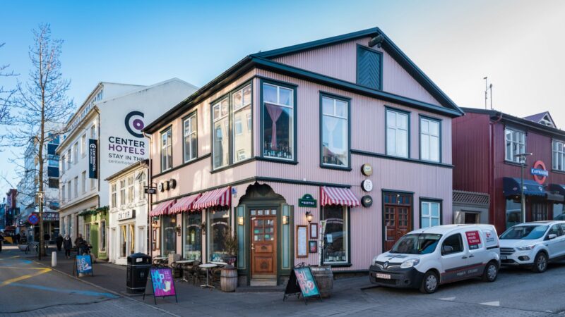 Corner two-storey building with striped awnings and parked vans
