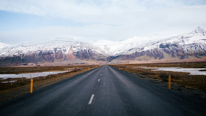 Straight road heading towards snow‑covered mountains