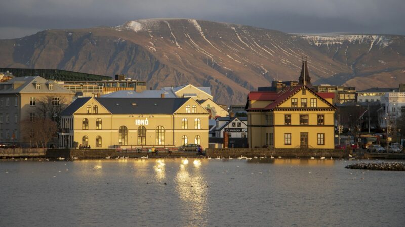 Old houses by a pond reflecting low sunlight