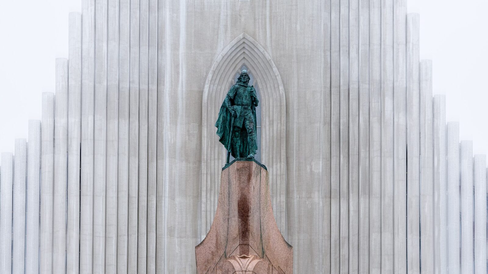 Statue in front of a tall ribbed church façade (Þjóðleikhúsið (the National Theatre))