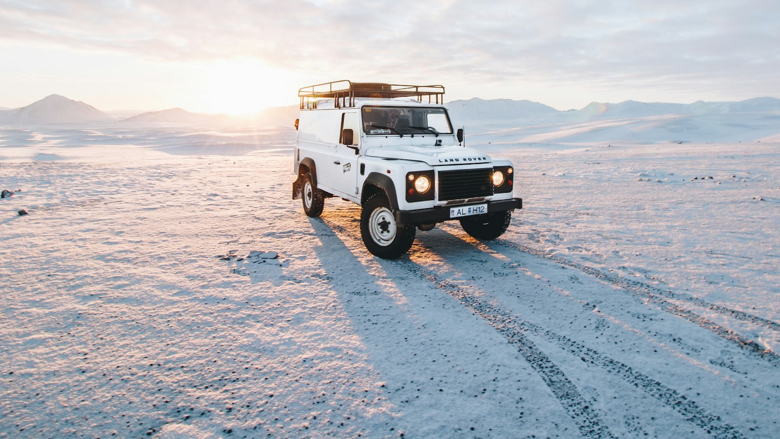 A 4x4 parked on a snowy plain at low sun