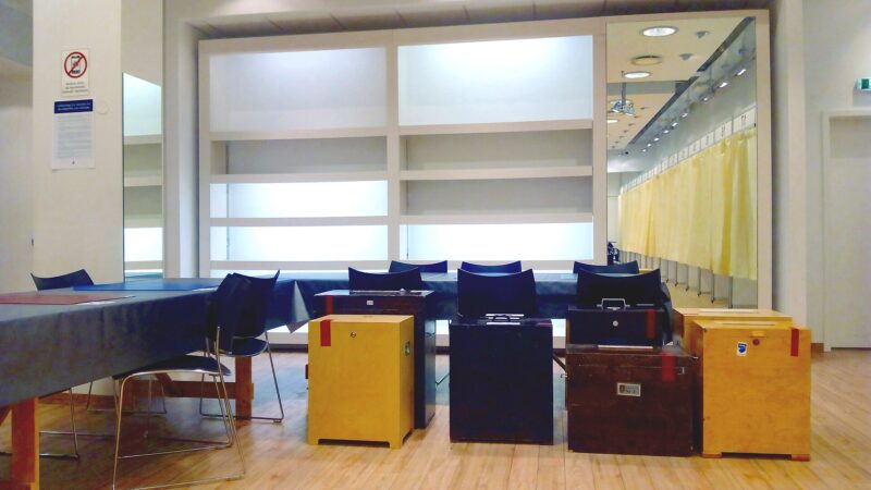 Polling station interior with tables, ballot boxes and voting booths