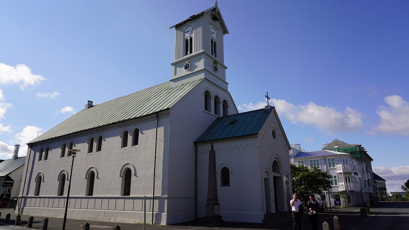 White church with clock tower against a blue sky (Alþingi)