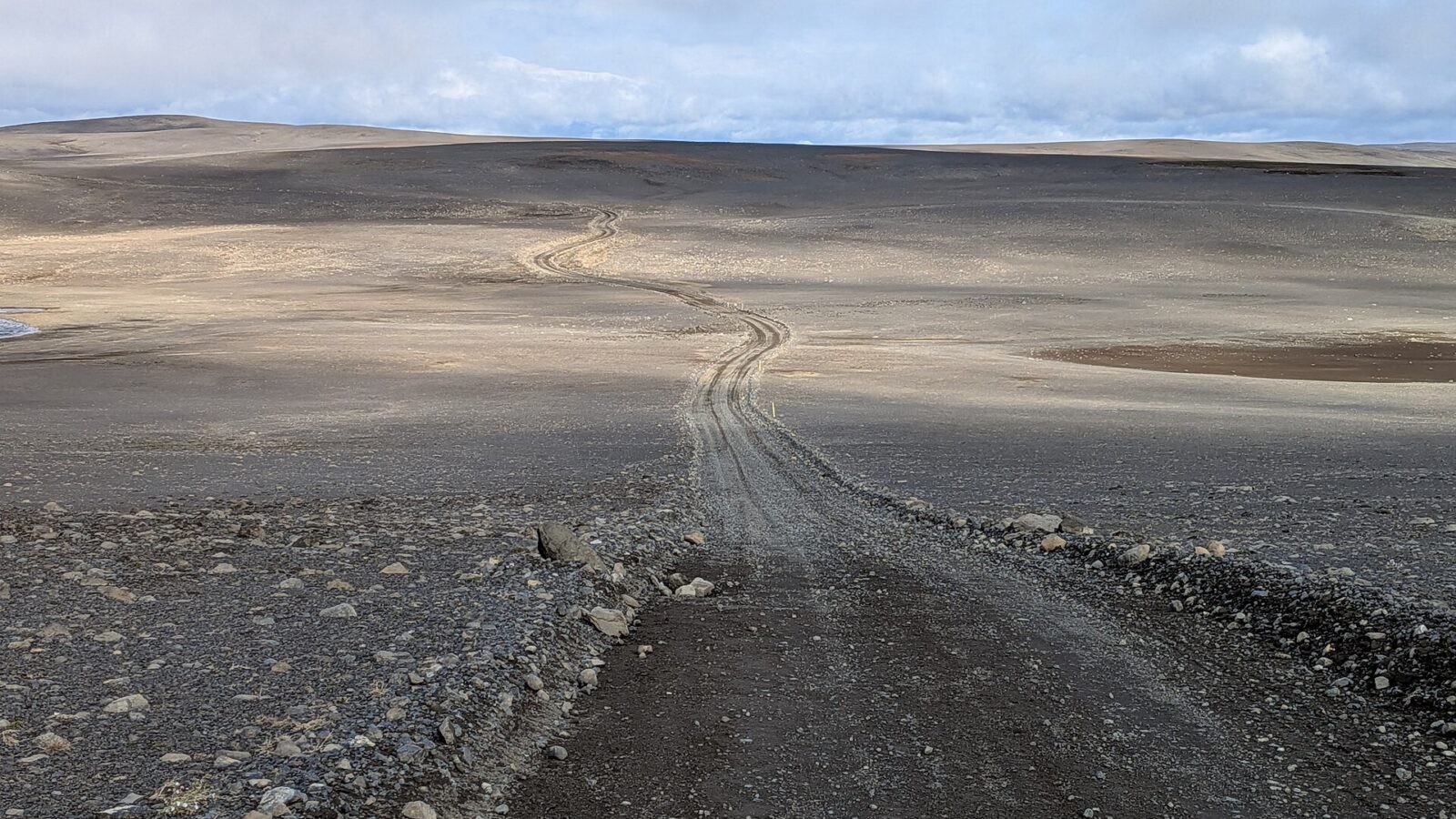 Winding gravel track across a wide, rocky plain and low hills