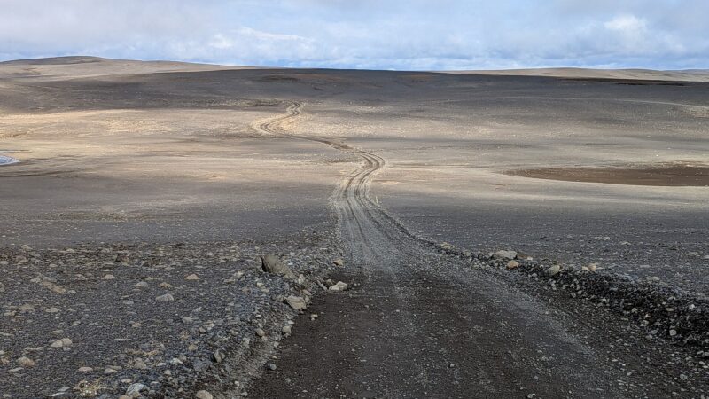 Winding gravel track across a wide, rocky plain and low hills