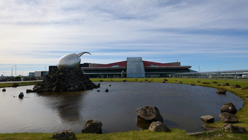 Exterior view of an airport terminal with sculpture and pond (Keflavík Airport)