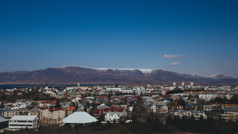 City foreground with mountains and clear blue sky behind (Mosfellsheiði)