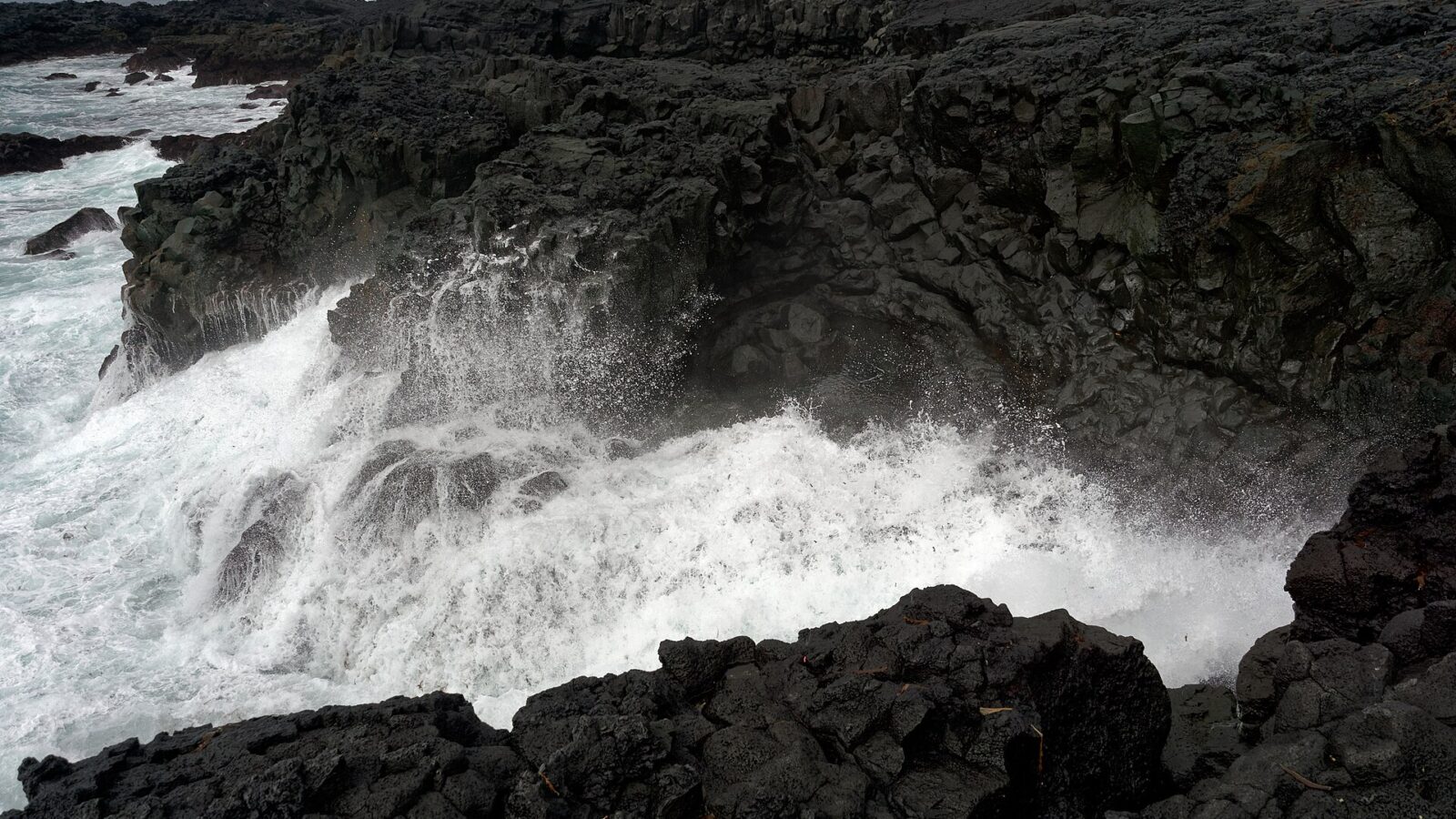 Waves crashing against dark volcanic cliffs