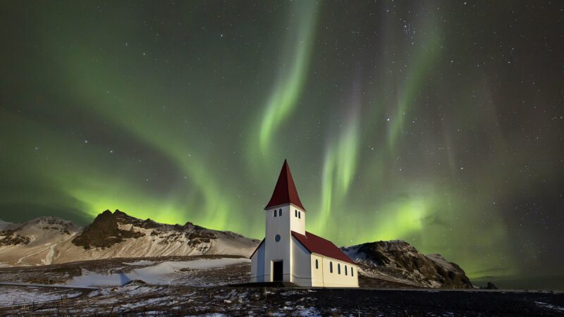 Small church under aurora borealis in a starry sky