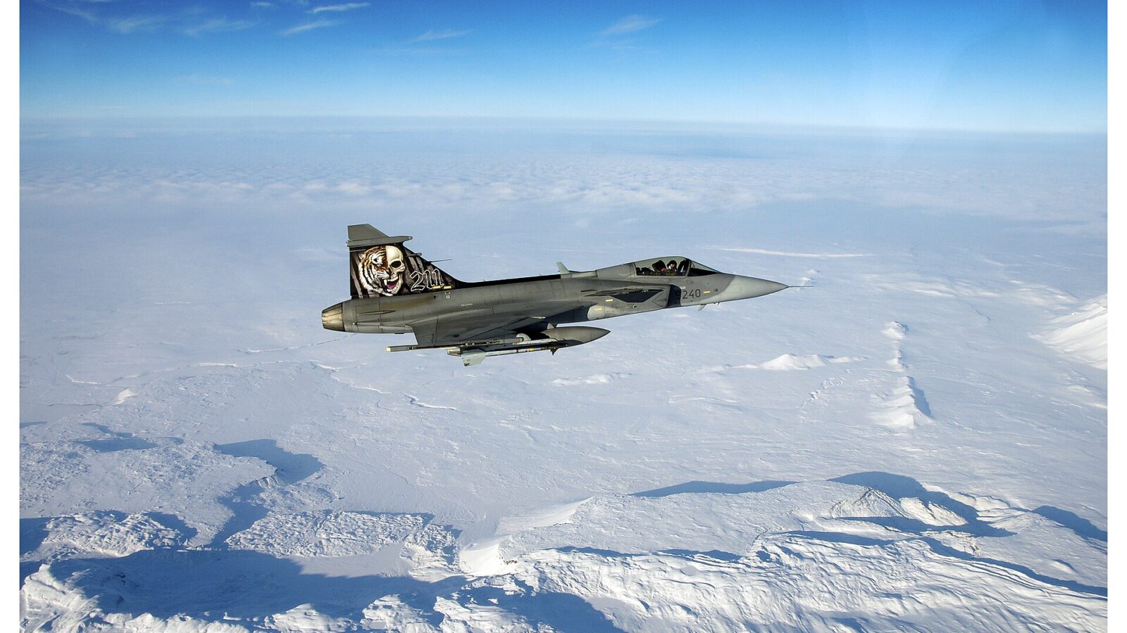 A fighter jet flying over snowy terrain