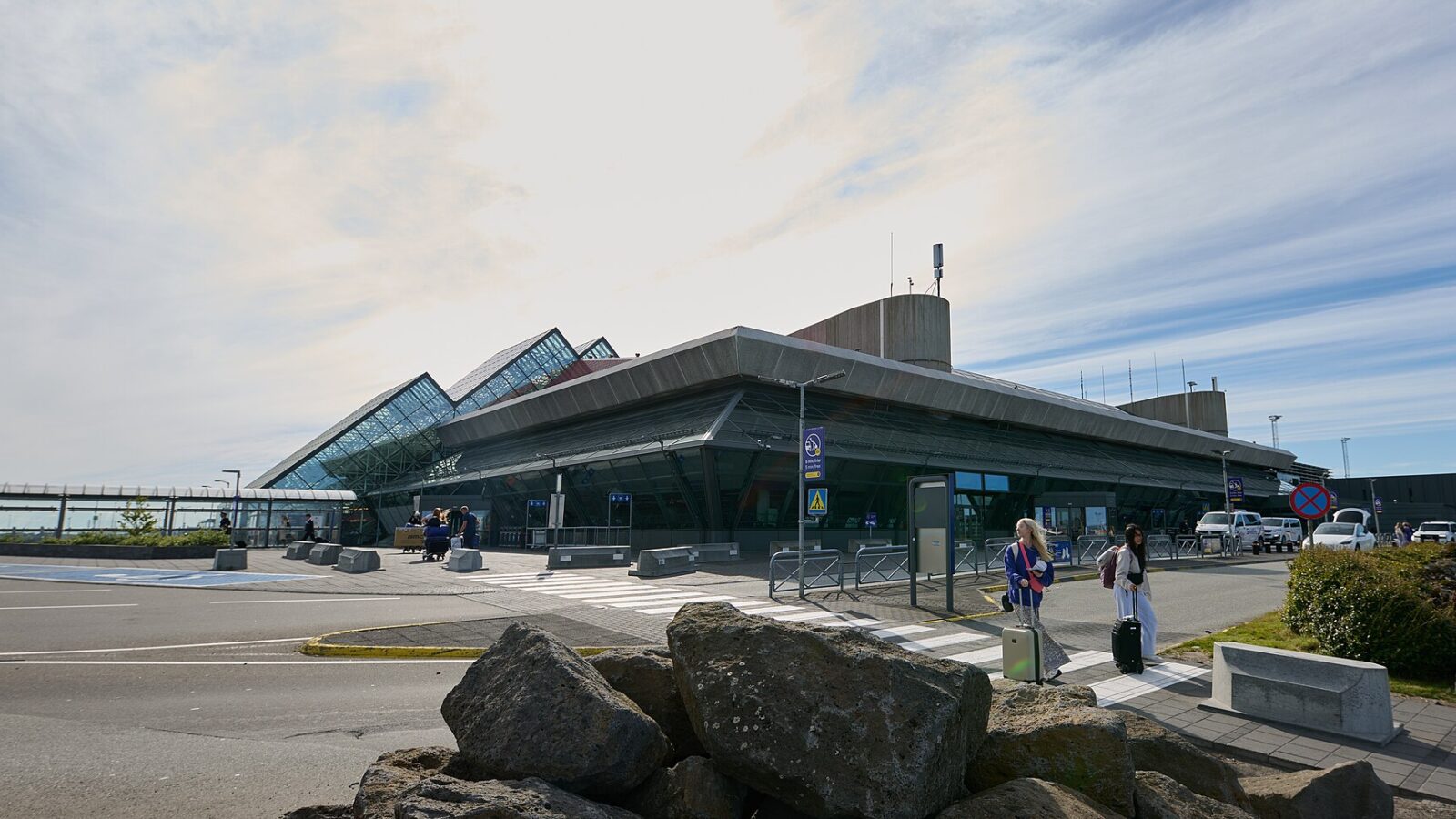 Airport terminal exterior with passengers and drop-off area (Keflavík Airport)