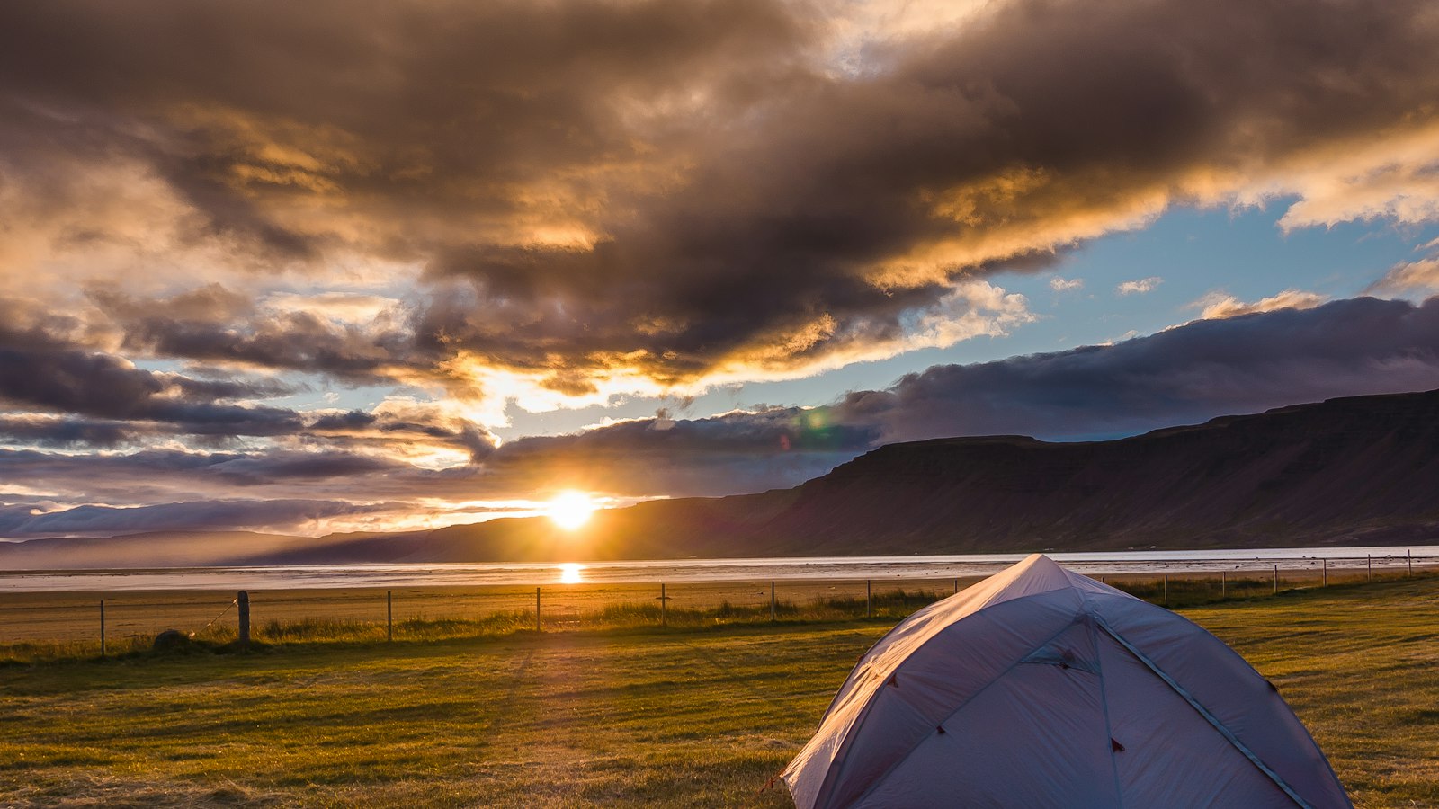 A tent pitched on a plain at sunset