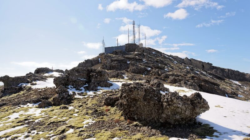 Rocky hill with communications masts and patches of snow (Grindavík)