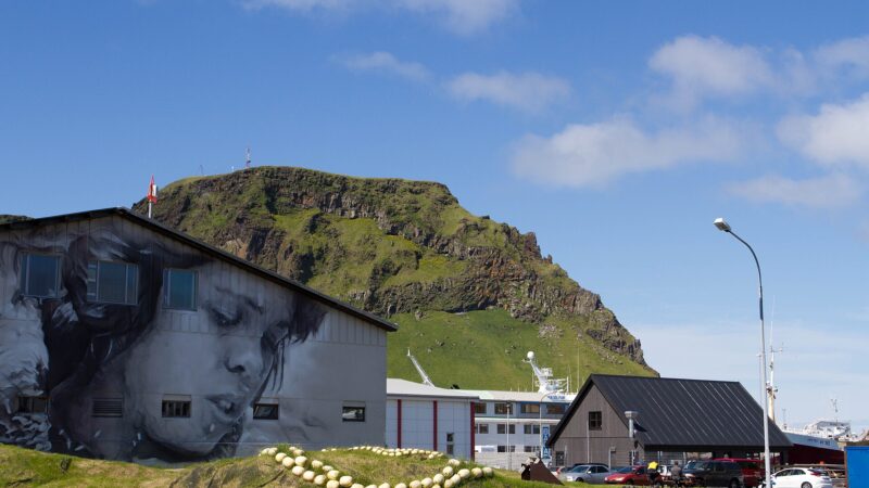 Harbour buildings, mural and grassy slope with buoys (Vestmannaeyjar)