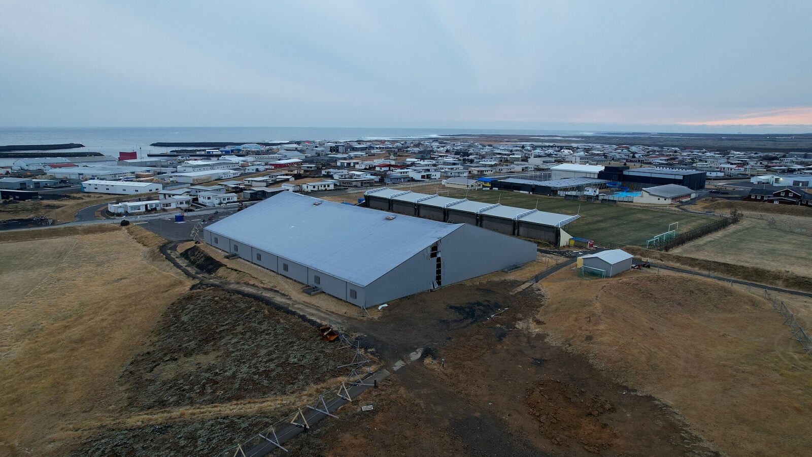 Wide view of the town, harbour and coastal buildings from a hill (Grindavík)
