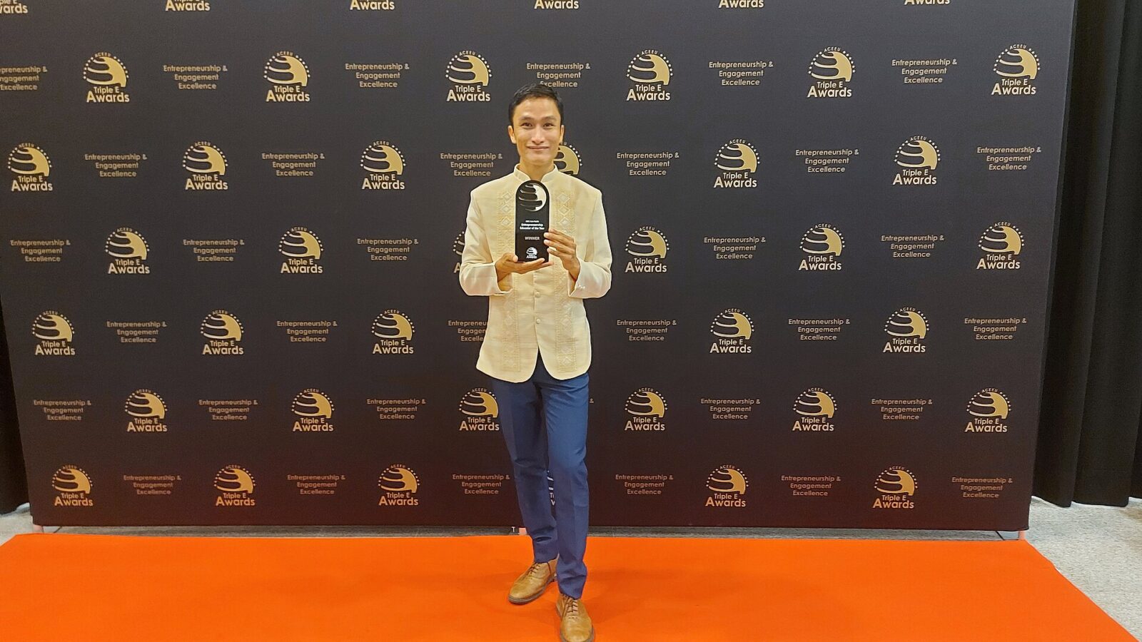 Person holding a trophy in front of a step-and-repeat awards backdrop (Barcelona)