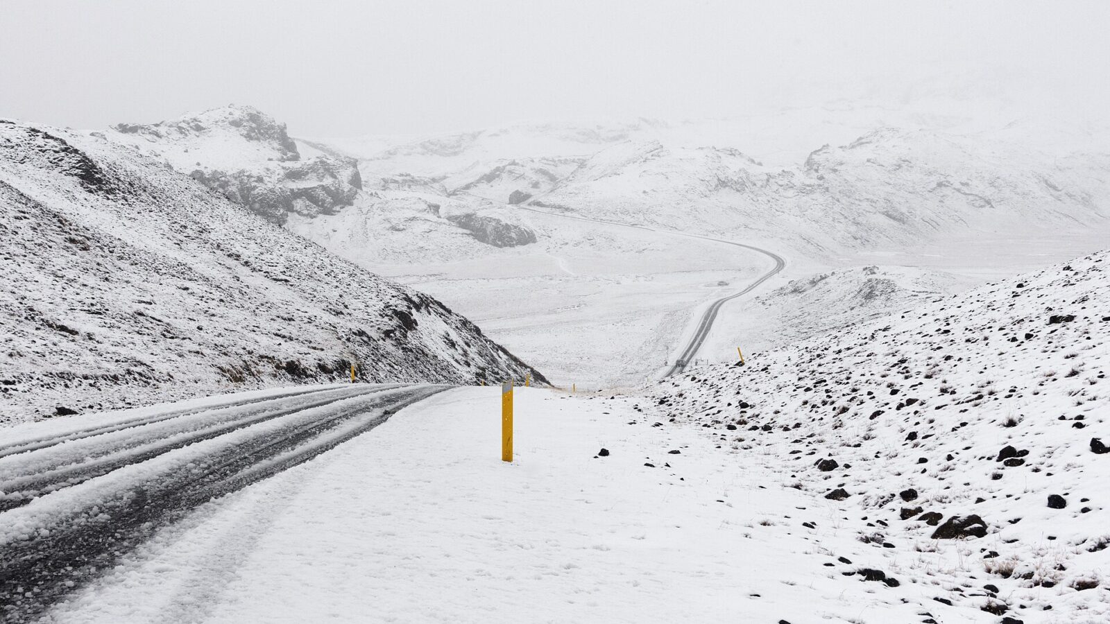 Snow-covered road and hills in a whiteout