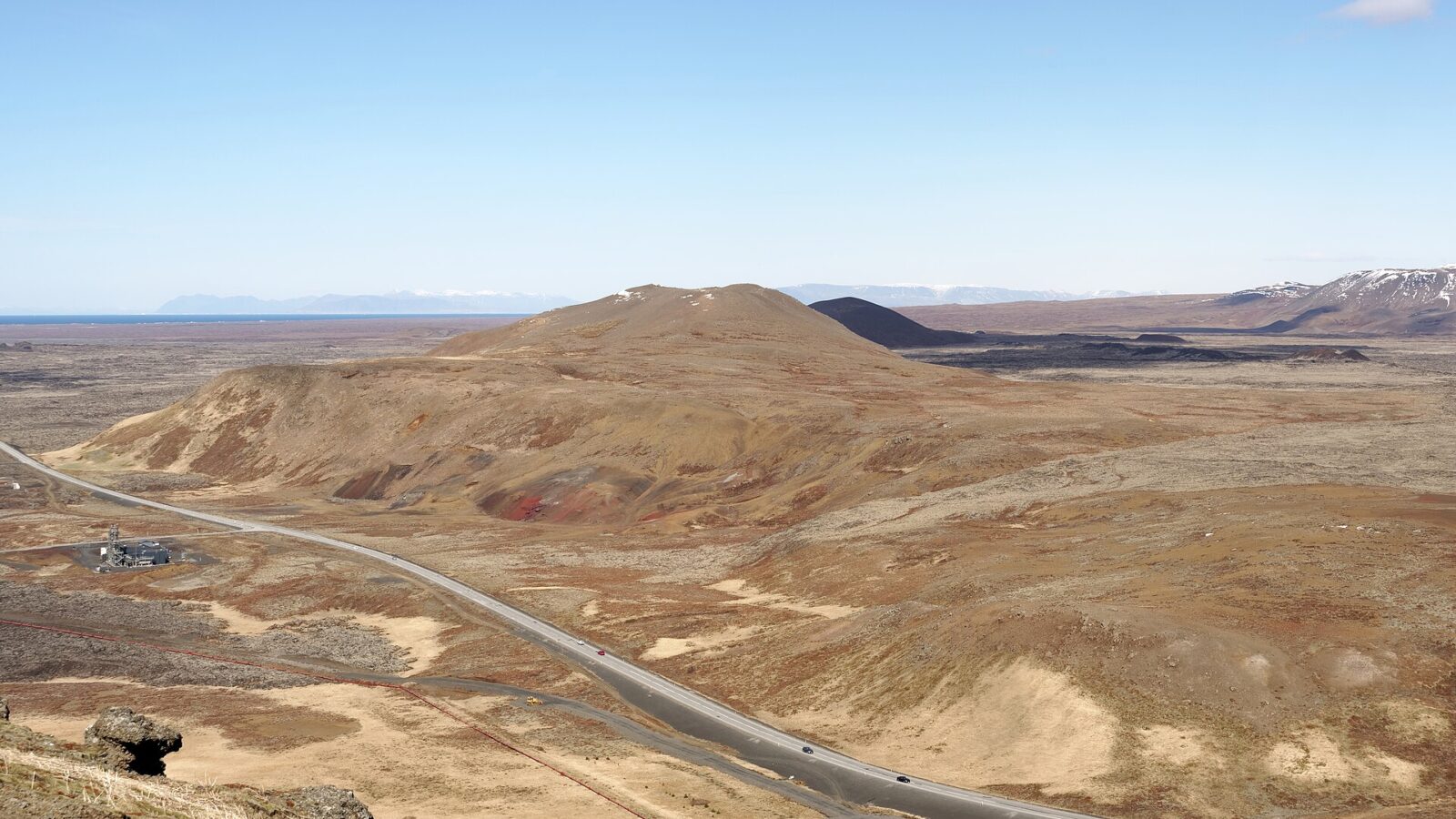 Wide view over volcanic cones, road and geothermal facility in a lava plain (Svartsengi)