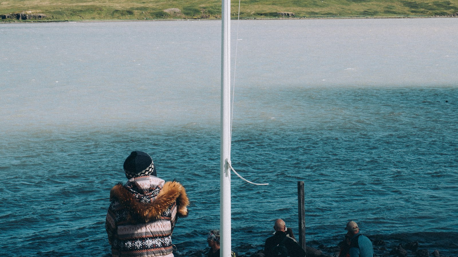 People looking out over a bay with a flagpole in the foreground