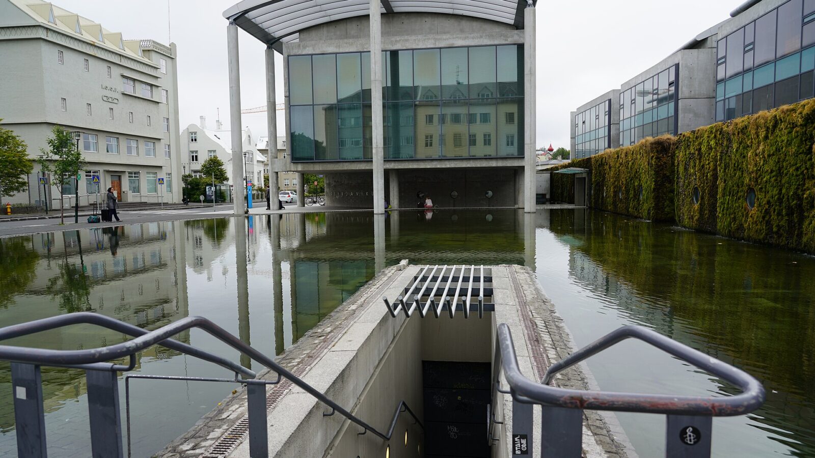 City hall building reflected in a rectangular pool with staircase in foreground (Reykjavík)