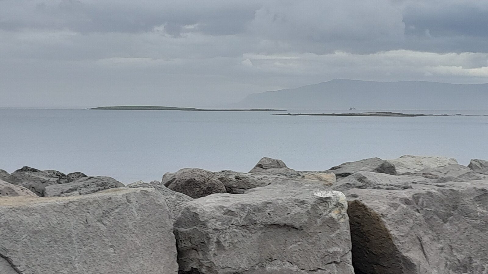 Sea and low islands beyond a rocky breakwater (höfuðborgarsvæðið)